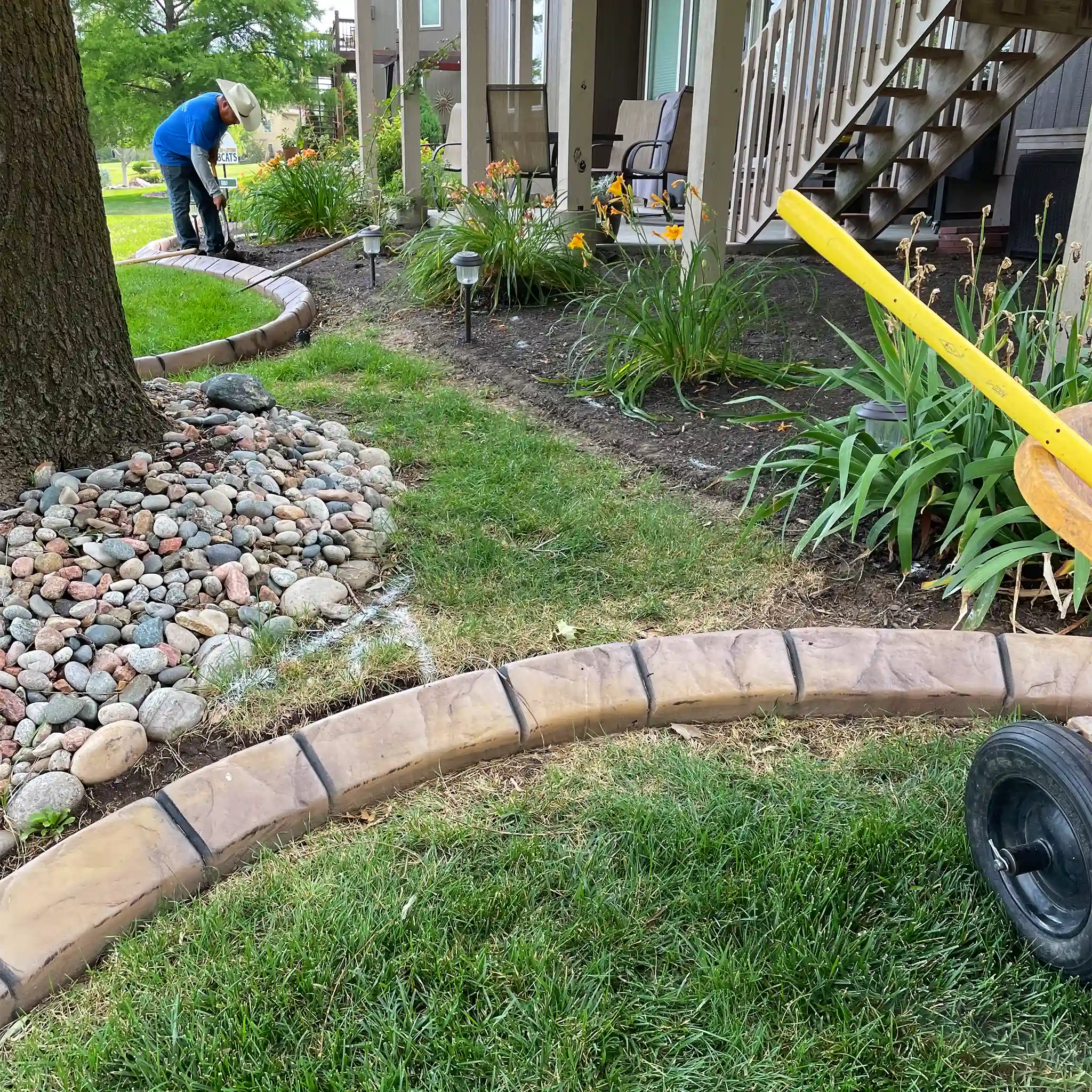 A worker prepares a backyard space prior to installing a new stone pathway.